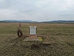 Régi emlékmű és háttérben a Vértes